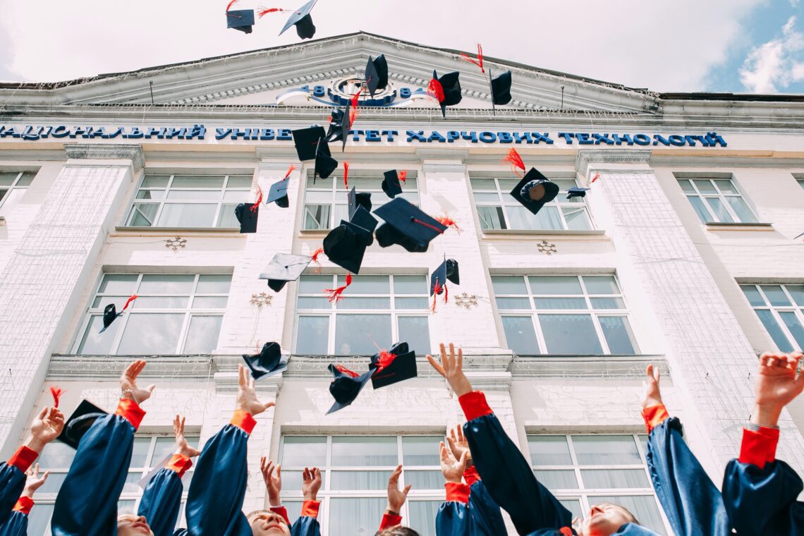 new grads throwing their caps in front of the school