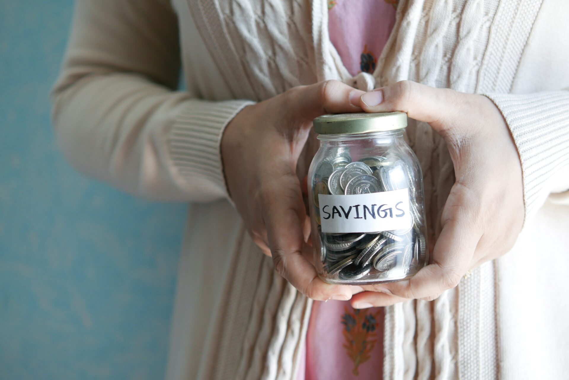 a person holding a jar of coins labeled as savings